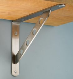 a close up of a metal bracket on a wooden shelf with wood planks in the background