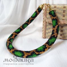 a green and gold beaded necklace next to a purse