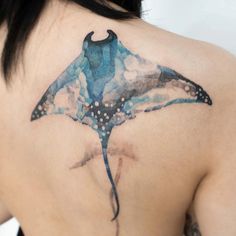 the back of a woman's shoulder with a blue and black tattoo design on it