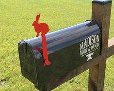 a black mailbox with a red sticker on it in front of some grass