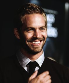 a smiling man in a sweater and tie
