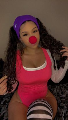 a woman wearing a clown nose sitting on top of a bed