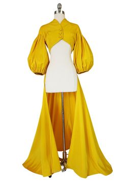 a mannequin wearing a yellow dress with long sleeves and an open front cape