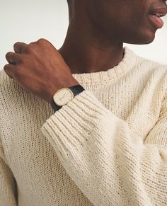 a man wearing a watch on his left hand and a white sweater on his right