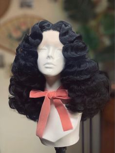 a mannequin head with black hair and a pink bow