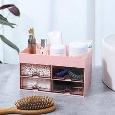 a wooden brush and some cosmetics on a table next to a container with other items in it