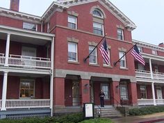 an old brick building with american flags on the front and second story balconies