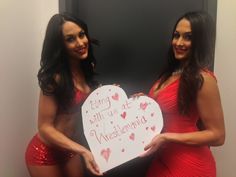 two women in red dresses holding a heart shaped sign