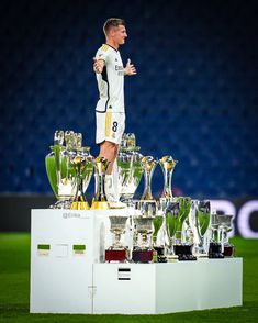 a man standing on top of a pile of trophies in the middle of a field