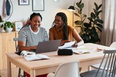 two women sitting at a table with laptops