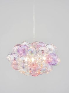 a chandelier made out of bubble balls hanging from the ceiling in front of a gray wall