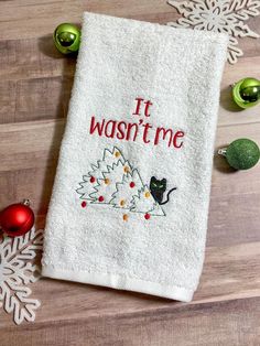 a white towel that says it wastime next to christmas ornaments on a wooden floor