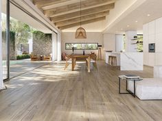 an open living room and dining area with wood flooring, white walls and ceiling