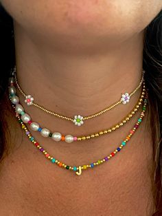 a woman wearing a multi - colored beaded necklace with flowers on the bottom and sides