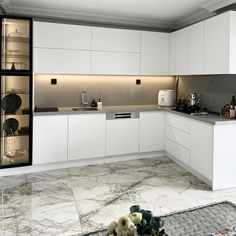 a kitchen with white cabinets and marble flooring is pictured in this image, there are flowers on the table