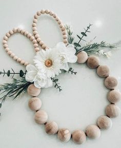 a wooden beaded necklace with white flowers and greenery