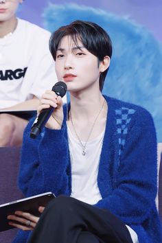 the young man is holding a microphone in his hand and looking at something while sitting down