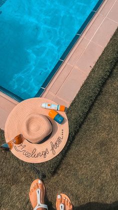 someone's feet and hat by the edge of a swimming pool with an inflatable raft