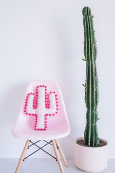 a cactus sitting next to a pink chair with the words how to diy a pom - pom cactus pillow