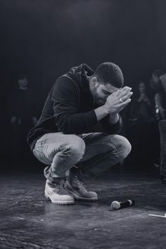 a black and white photo of a man kneeling on the ground with his hands together