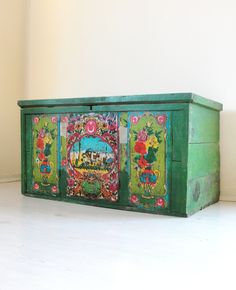 an old green painted chest with flowers and animals on it