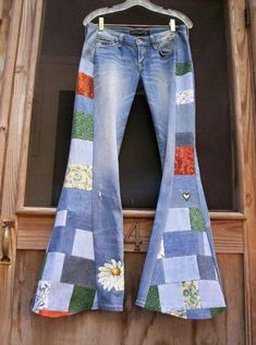 a pair of jeans with patchwork on them hanging from a clothes hanger in front of a wooden door