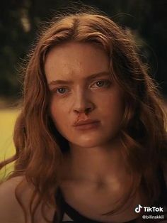 a close up of a person with freckles on her face and hair in the background