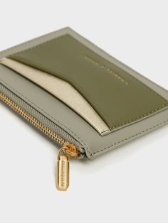 a green wallet with a gold tag on the front and zippered closure is shown