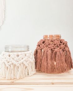 two crocheted baskets sitting on top of a wooden table next to a jar