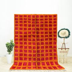 an orange and blue blanket sitting on top of a wooden table next to a potted plant