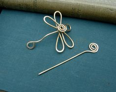 a pair of knitting needles sitting on top of a blue surface next to an old book