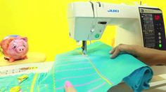 a person is using a sewing machine to sew on a piece of fabric with a piggy bank figurine in the background