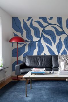 a blue and white living room with a black leather couch in front of a wall mural