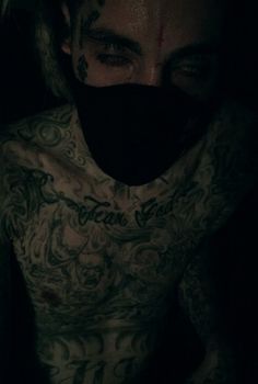 a man with tattoos on his chest wearing a black mask