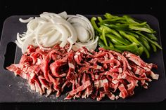 chopped meat, onions and green beans on a black cutting board with a plastic spatula