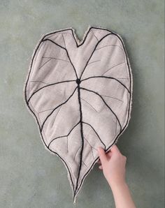 a person holding up a heart shaped cushion with black lines on the bottom and sides