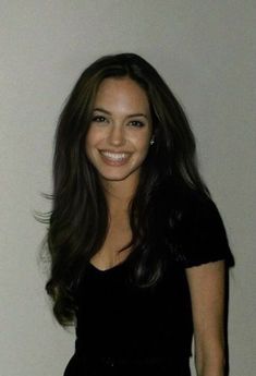 a woman with long dark hair smiling at the camera