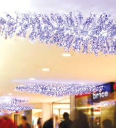 people are walking through a shopping mall with chandeliers hanging from the ceiling in front of them