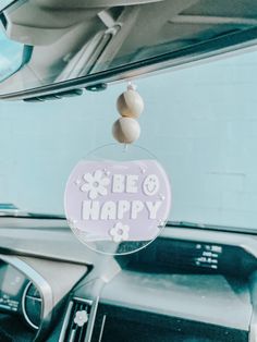 a car dashboard with a sign that says be happy hanging from it's windshield