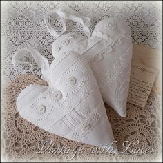 two white heart shaped pillows sitting on top of a doily