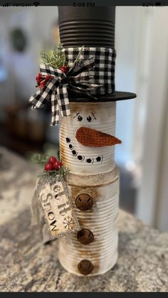 a snowman made out of tin cans with a top hat and scarf on it