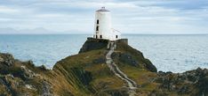 a lighthouse sitting on top of a rocky cliff next to the ocean with stairs leading up to it