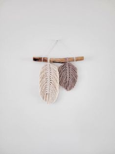 three feathers hanging from a wooden stick on a white wall