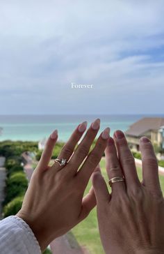 two hands reaching up towards each other with the ocean in the background