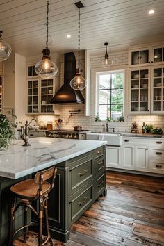 a large kitchen with an island in the middle and lots of lights hanging from the ceiling