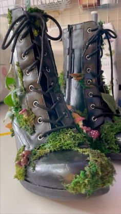 a pair of boots with moss growing on the inside and outside, sitting on top of a table