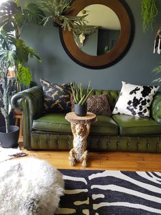 a living room with green couches and potted plants on the wall next to it