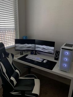 a computer desk with two monitors and a keyboard on it, in front of a window