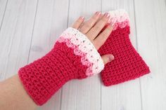 a woman's hand holding onto a red and white crocheted mitt