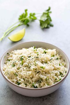 a white bowl filled with rice and garnished with cilantro on the side